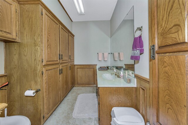 bathroom featuring toilet, a wainscoted wall, tile patterned floors, and vanity