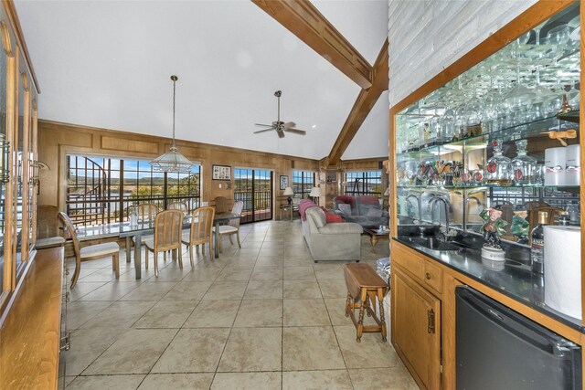 interior space featuring high vaulted ceiling, beamed ceiling, light tile patterned flooring, and wooden walls