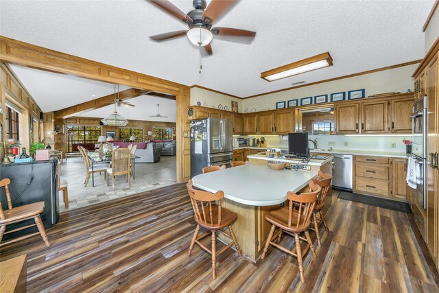 kitchen with open floor plan, light countertops, appliances with stainless steel finishes, a center island, and brown cabinetry