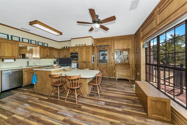 kitchen featuring appliances with stainless steel finishes, a center island, brown cabinets, and light countertops