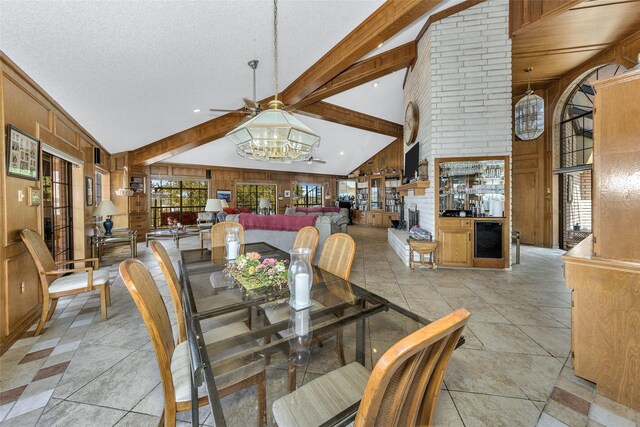 dining space with a textured ceiling, high vaulted ceiling, a notable chandelier, wood walls, and beamed ceiling