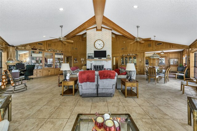 living room featuring a textured ceiling, ceiling fan, wood walls, and a brick fireplace