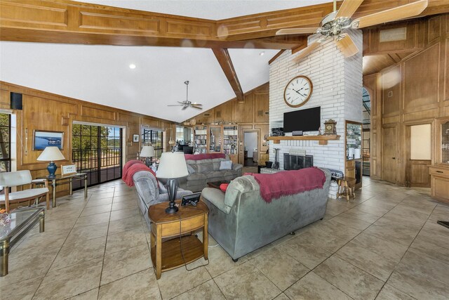 living room with ceiling fan, beamed ceiling, wood walls, and a brick fireplace