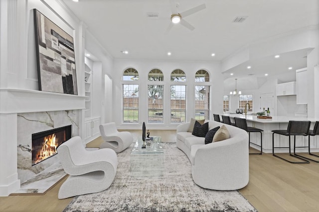 living area with light wood-type flooring, ornamental molding, a fireplace, and visible vents