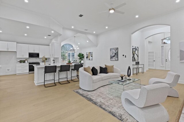 living area featuring visible vents, arched walkways, ornamental molding, light wood-style floors, and recessed lighting