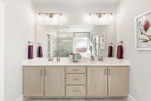 full bath featuring a sink, double vanity, a shower stall, and baseboards