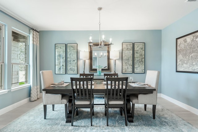 dining room featuring a chandelier, visible vents, light wood-style flooring, and baseboards