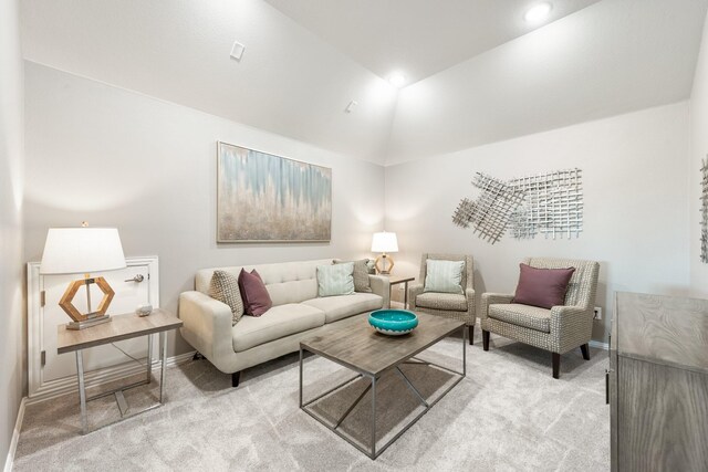 living area featuring light colored carpet, vaulted ceiling, and baseboards