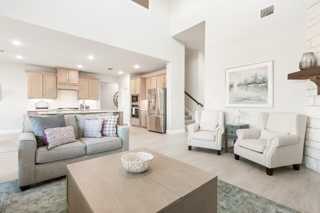 living room featuring stairway, light wood-style flooring, visible vents, and recessed lighting