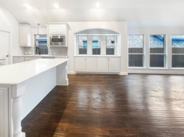 kitchen featuring dark wood-style floors, decorative light fixtures, light countertops, stainless steel microwave, and white cabinets