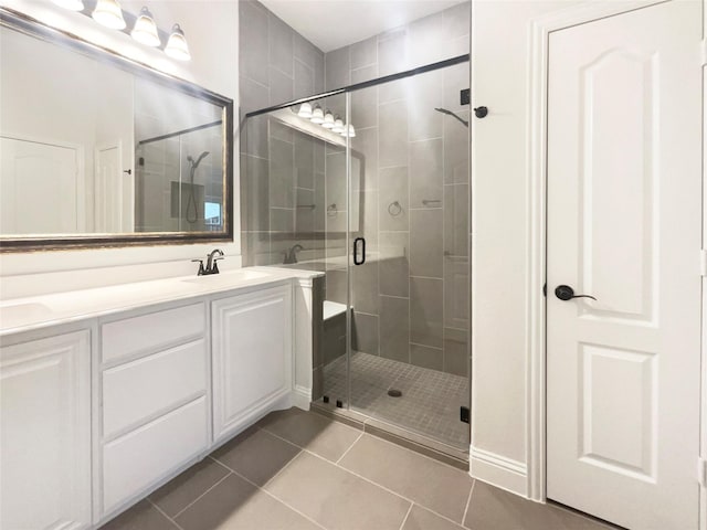 bathroom with a stall shower, double vanity, a sink, and tile patterned floors