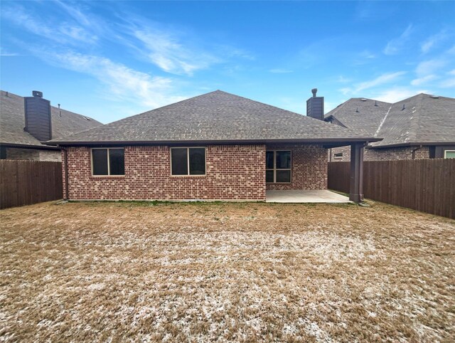 back of house with a patio area, a fenced backyard, roof with shingles, and brick siding