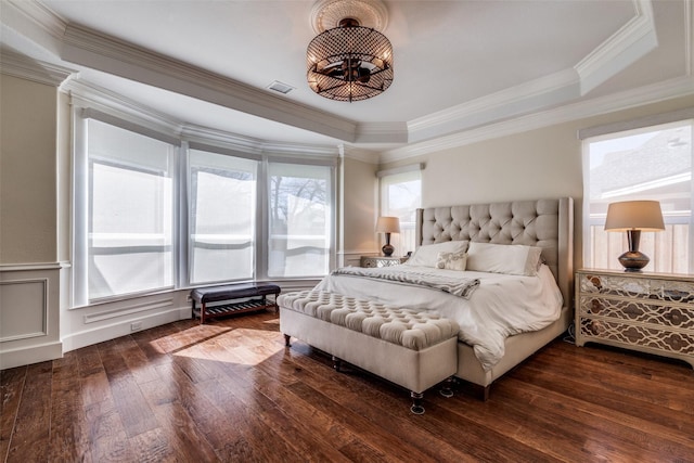 bedroom featuring ornamental molding, a tray ceiling, dark wood-style flooring, and visible vents