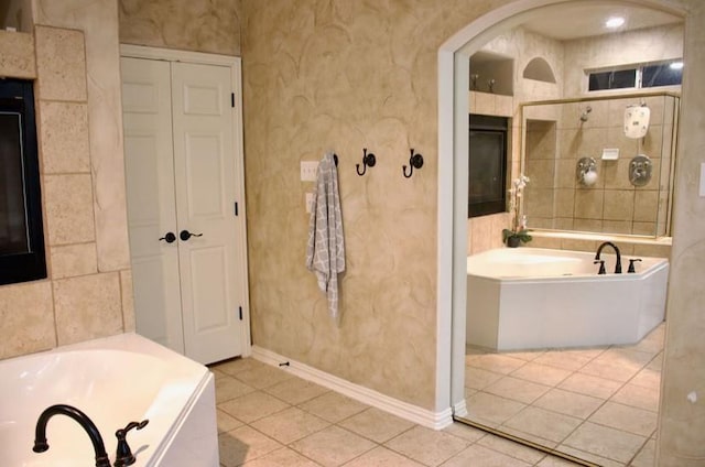 full bath with a garden tub, tile patterned flooring, baseboards, and a closet