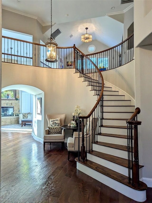 stairs featuring a notable chandelier, crown molding, a high ceiling, and wood finished floors