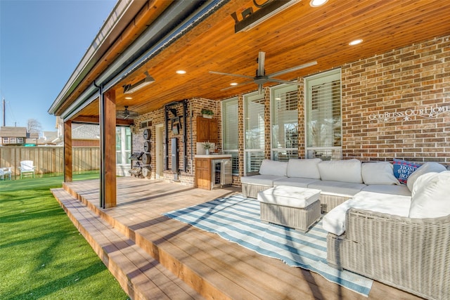 deck with outdoor lounge area, ceiling fan, and fence