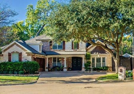 view of front of property with driveway, a standing seam roof, and brick siding