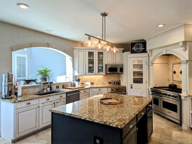 kitchen with glass insert cabinets, a center island, stainless steel appliances, white cabinetry, and a sink