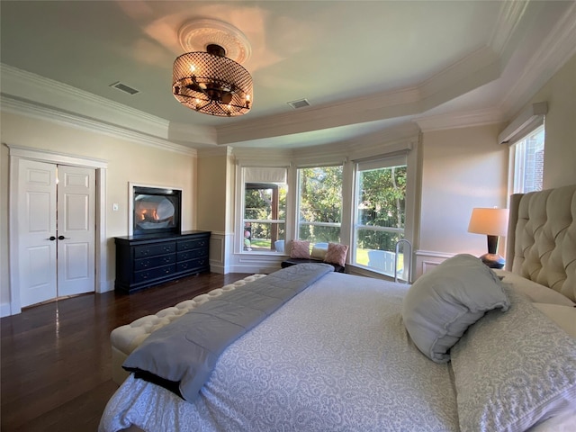 bedroom with a tray ceiling, visible vents, and multiple windows