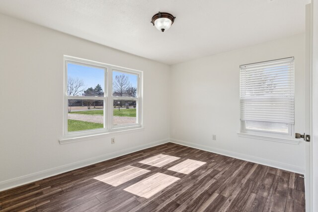 spare room featuring dark wood finished floors and baseboards