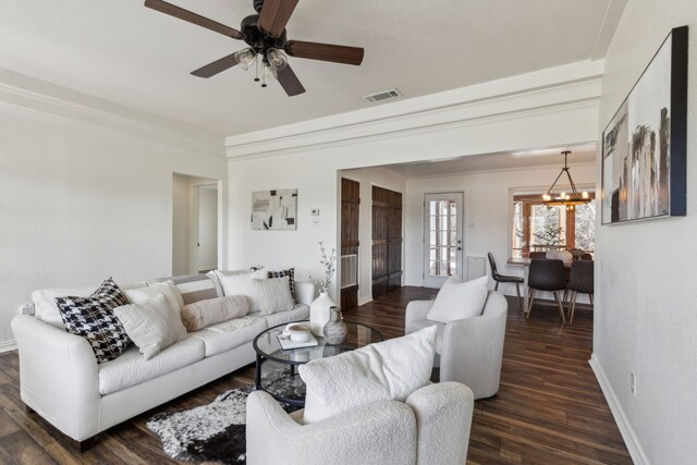 living room with visible vents, dark wood-type flooring, ornamental molding, baseboards, and ceiling fan with notable chandelier