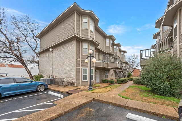 view of property with uncovered parking, central AC, and stairs