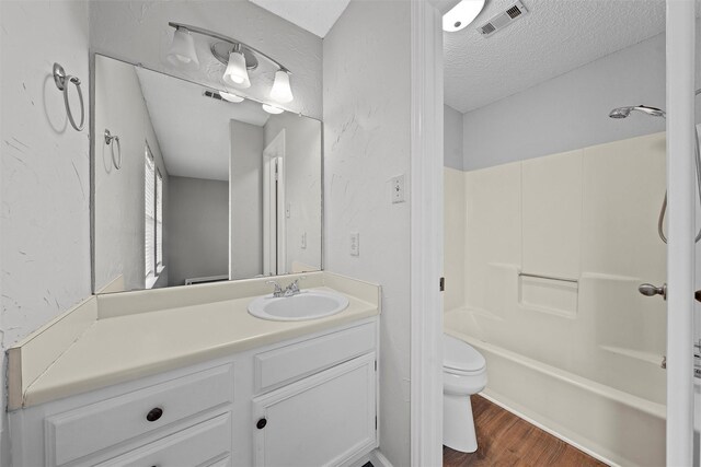 bathroom featuring visible vents, toilet, vanity, a textured ceiling, and wood finished floors