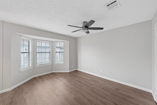 spare room with dark wood finished floors, visible vents, ceiling fan, a textured ceiling, and baseboards