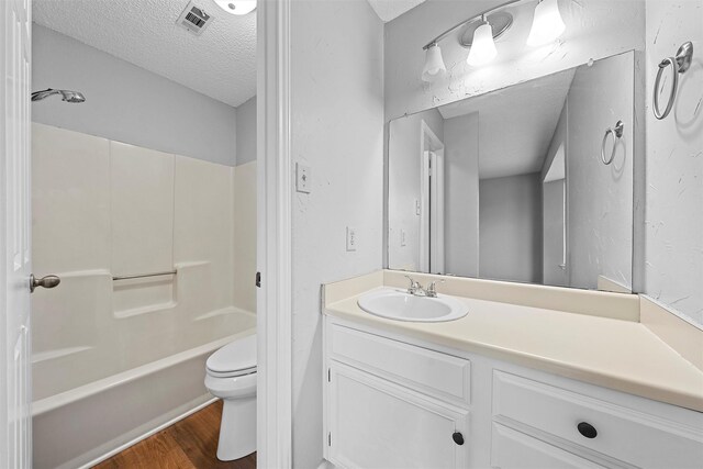 full bathroom with shower / bath combination, visible vents, toilet, a textured ceiling, and wood finished floors