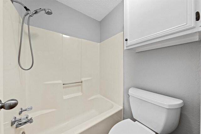 bathroom with toilet, a textured ceiling, and shower / bathing tub combination