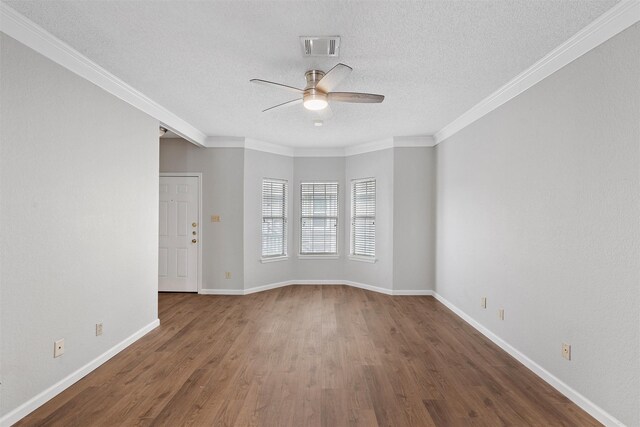 empty room with baseboards, ceiling fan, dark wood-type flooring, a textured ceiling, and crown molding