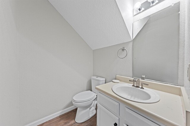 bathroom with baseboards, a textured wall, toilet, wood finished floors, and vanity