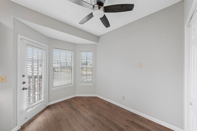 empty room featuring dark wood-type flooring, a textured ceiling, baseboards, and a ceiling fan