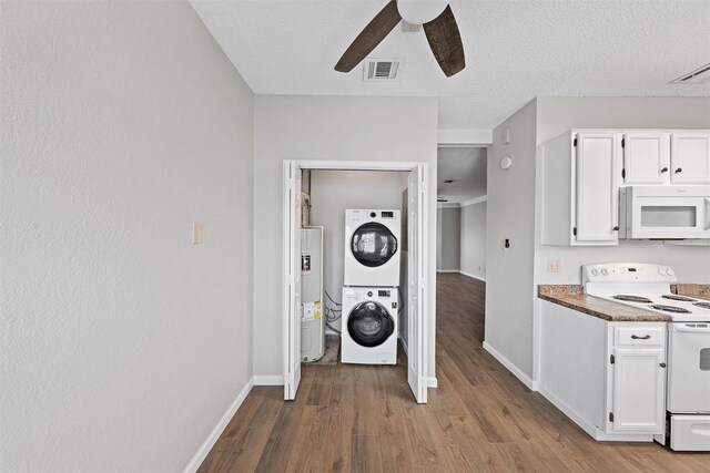 kitchen featuring stacked washer / dryer, white appliances, visible vents, and white cabinets