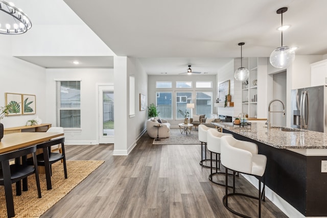 2417 Robin Way, Northlake, TX 76247 - kitchen with stainless steel refrigerator with ice dispenser, a sink, wood finished floors, light stone counters, and a kitchen bar