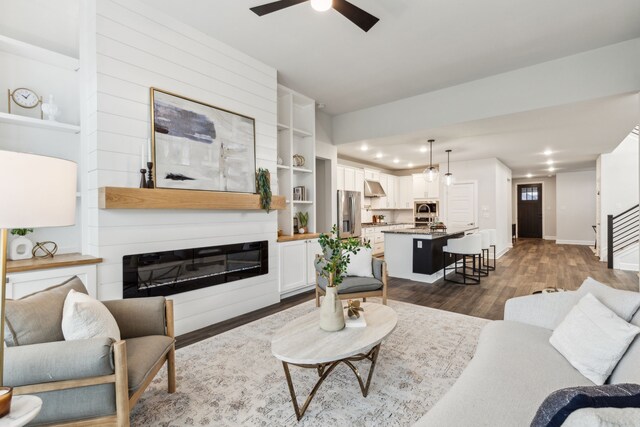 2417 Robin Way, Northlake, TX 76247 - living area featuring ceiling fan, dark wood-style flooring, baseboards, a glass covered fireplace, and stairs