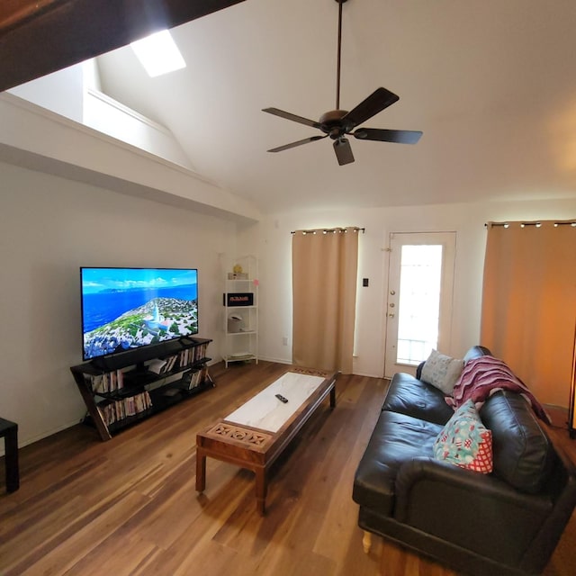 living area featuring ceiling fan, high vaulted ceiling, a skylight, and wood finished floors