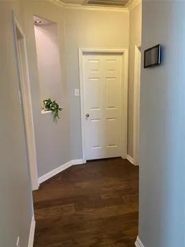 hall featuring dark wood-style floors, ornamental molding, and baseboards