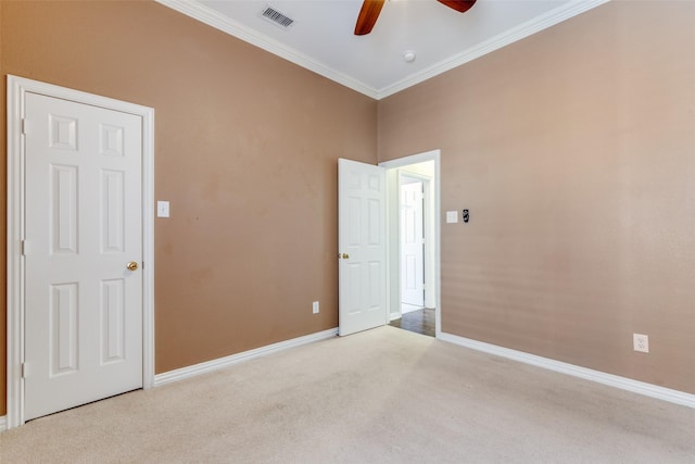 empty room featuring light carpet, a ceiling fan, baseboards, visible vents, and crown molding