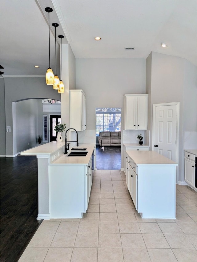 kitchen featuring decorative light fixtures, light countertops, white cabinets, a sink, and a peninsula