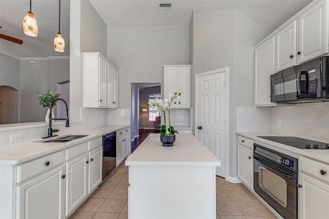 kitchen featuring white cabinets, a center island, black appliances, pendant lighting, and a sink