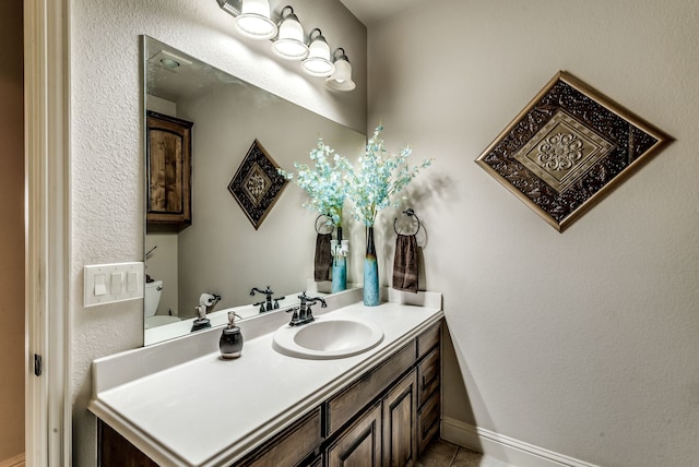 bathroom featuring baseboards, a textured wall, toilet, tile patterned floors, and vanity