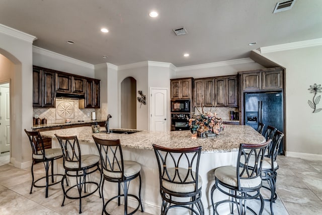 kitchen featuring arched walkways, black appliances, a spacious island, and visible vents