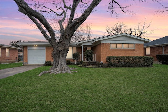 view of front of house featuring a yard, concrete driveway, brick siding, and a garage