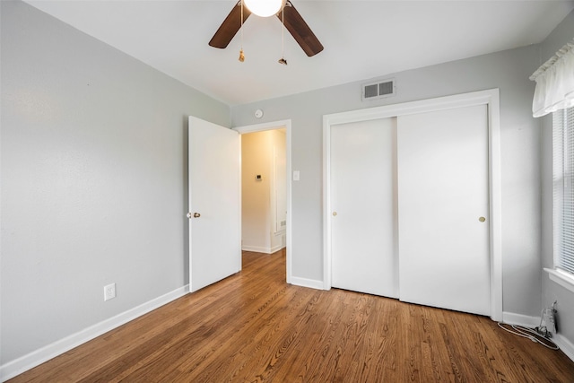 unfurnished bedroom featuring a closet, visible vents, baseboards, and wood finished floors