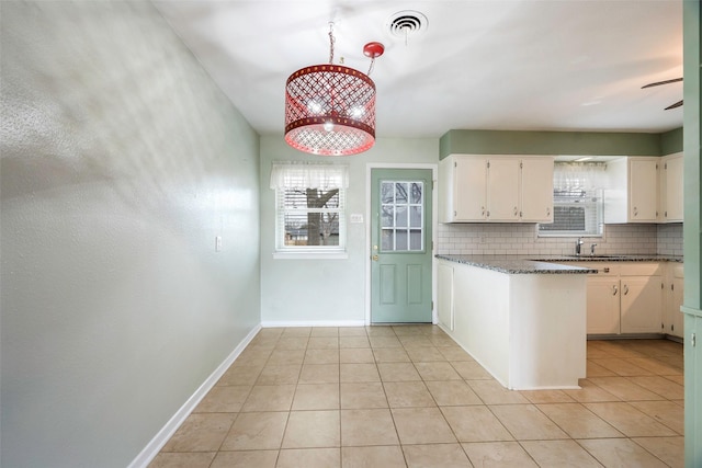 kitchen with light tile patterned floors, tasteful backsplash, white cabinets, and dark stone countertops