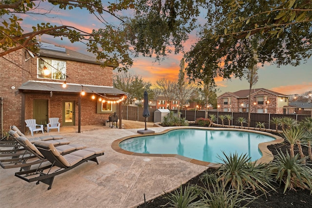 view of swimming pool with a patio area, a fenced backyard, a storage shed, and a fenced in pool