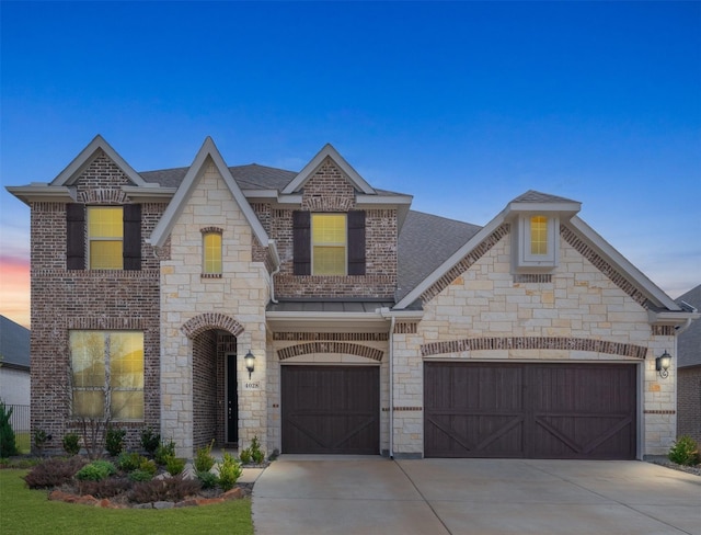 french country style house featuring a garage, concrete driveway, brick siding, and a shingled roof