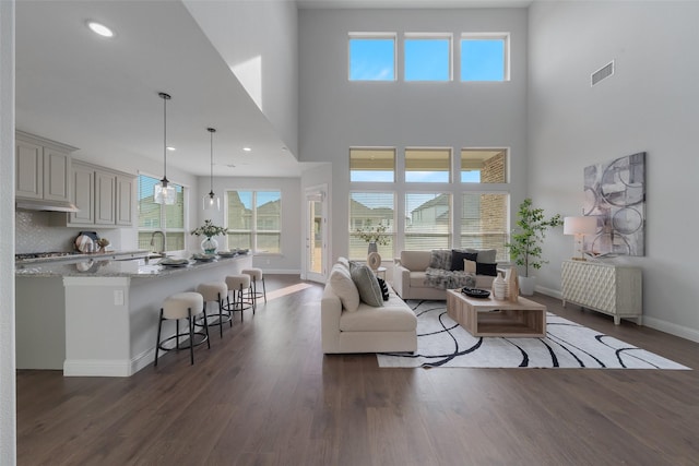 living room with a healthy amount of sunlight, visible vents, baseboards, and dark wood-style flooring