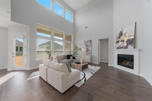 living room featuring a glass covered fireplace, wood finished floors, visible vents, and baseboards